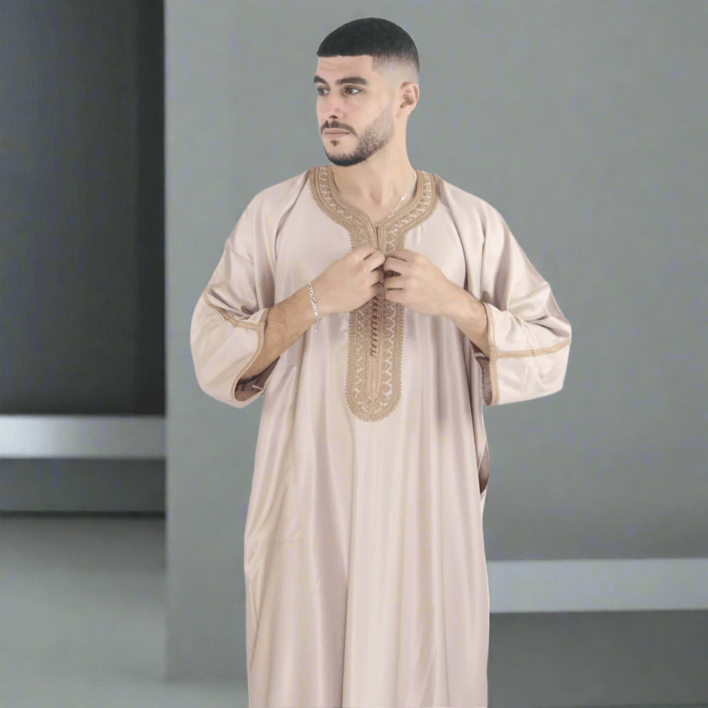 Man wearing a beige traditional outfit with intricate embroidery on a white background