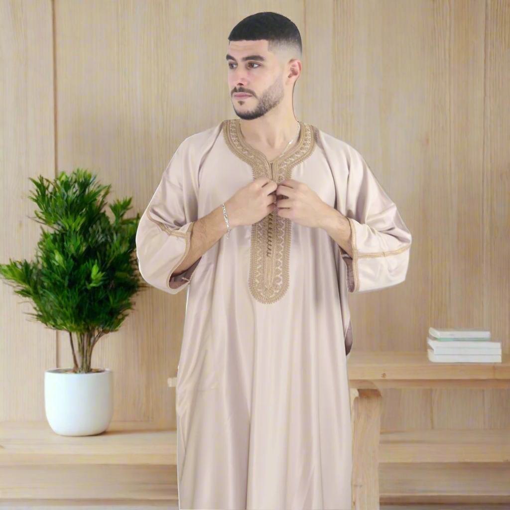 Man wearing a beige traditional outfit with intricate embroidery on a white background