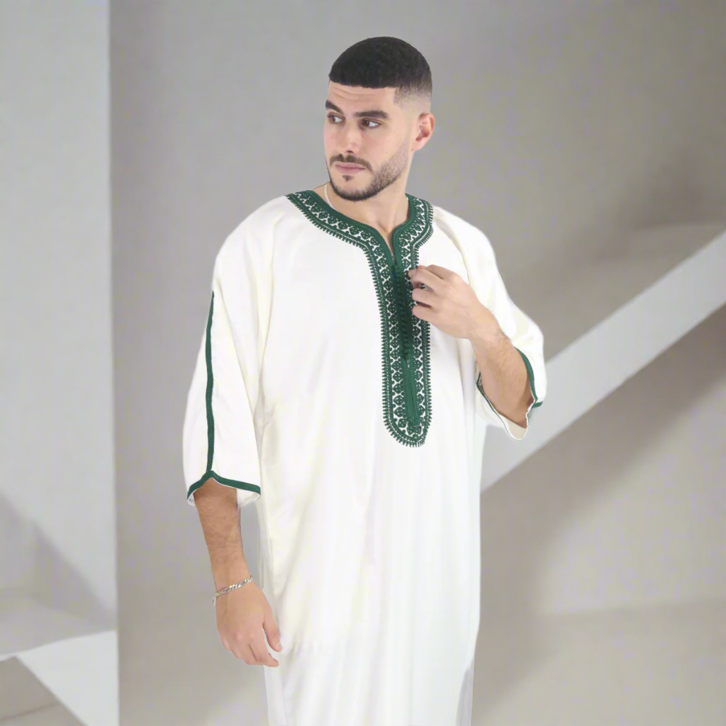 Man wearing a white outfit with green embroidery on a white background