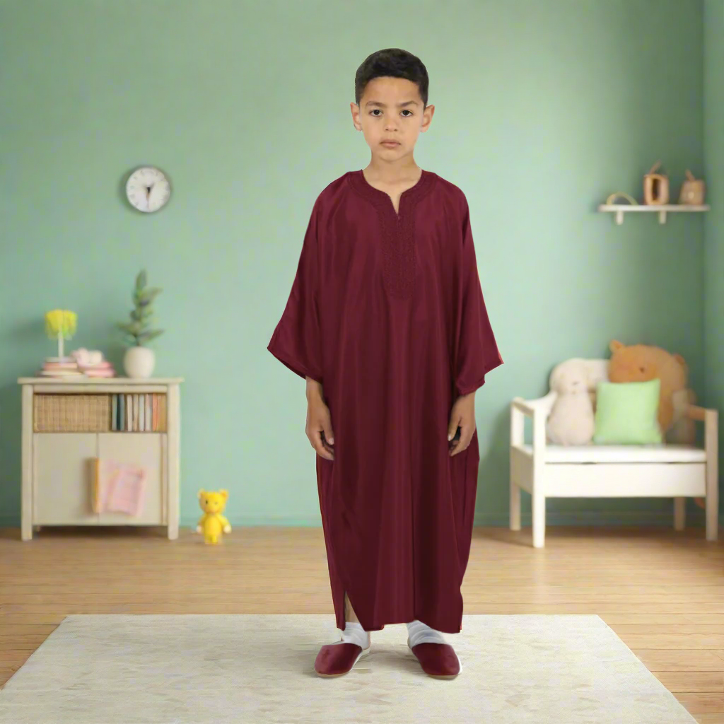 Child wearing a burgundy thobe on a white background